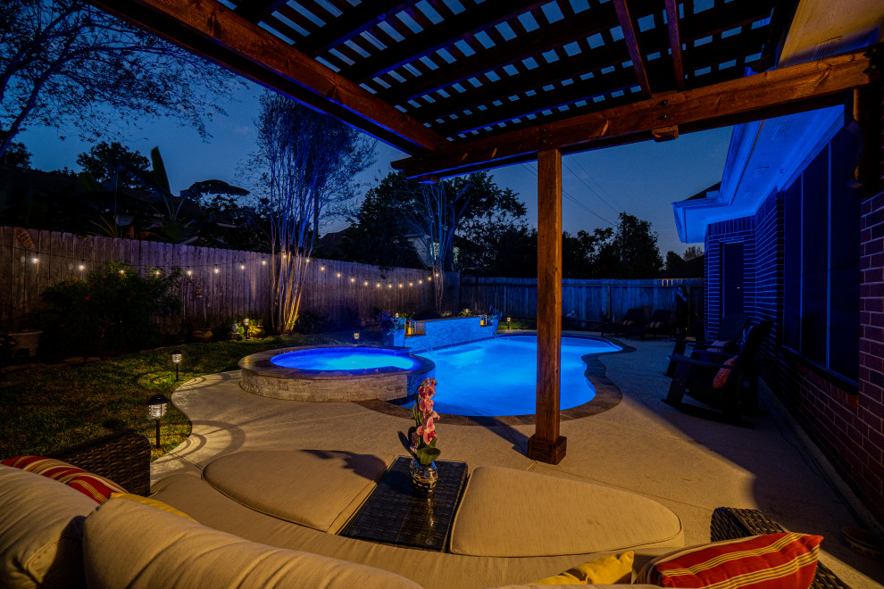 Photo of a mid-sized tropical backyard custom-shaped pool in Houston with decking.