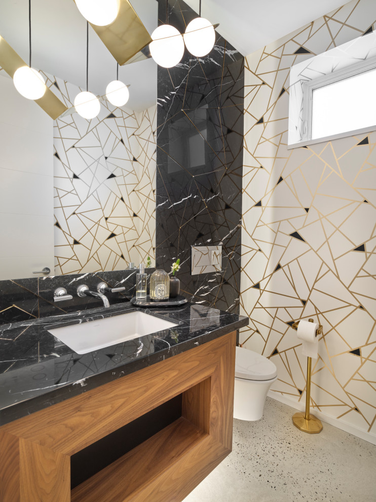 Design ideas for a small contemporary powder room in Edmonton with flat-panel cabinets, engineered quartz benchtops, medium wood cabinets, multi-coloured walls, concrete floors, an undermount sink, grey floor and black benchtops.