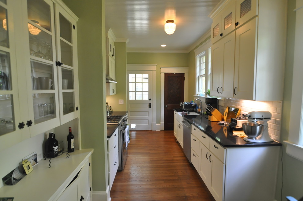 Photo of a mid-sized traditional eat-in kitchen in Raleigh with a farmhouse sink, shaker cabinets, white cabinets, quartz benchtops, white splashback, porcelain splashback, stainless steel appliances and medium hardwood floors.