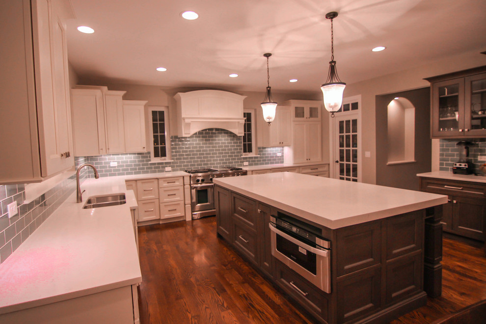 Enclosed kitchen - mid-sized transitional l-shaped dark wood floor enclosed kitchen idea in Chicago with recessed-panel cabinets, white cabinets, solid surface countertops, stainless steel appliances, an island, a double-bowl sink, blue backsplash and glass tile backsplash