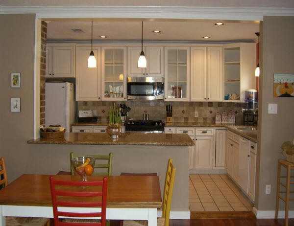Eat-in kitchen - large transitional l-shaped porcelain tile and beige floor eat-in kitchen idea in Houston with raised-panel cabinets, white cabinets, granite countertops, beige backsplash, travertine backsplash, white appliances and a peninsula