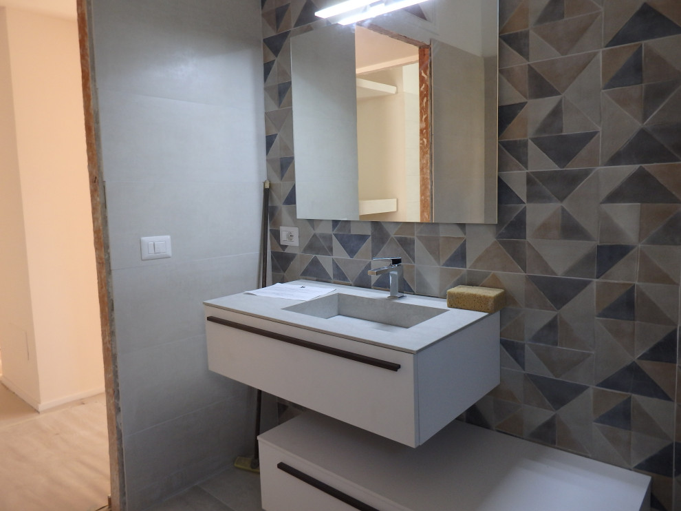 Photo of a mid-sized modern master bathroom in Rome with white cabinets, a drop-in tub, multi-coloured tile, porcelain tile, white walls, ceramic floors, a trough sink and grey floor.