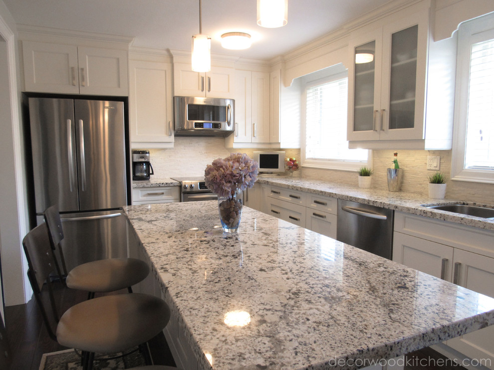 Inspiration for a mid-sized transitional l-shaped dark wood floor enclosed kitchen remodel in Toronto with an undermount sink, flat-panel cabinets, white cabinets, granite countertops, white backsplash, stone tile backsplash, stainless steel appliances and an island