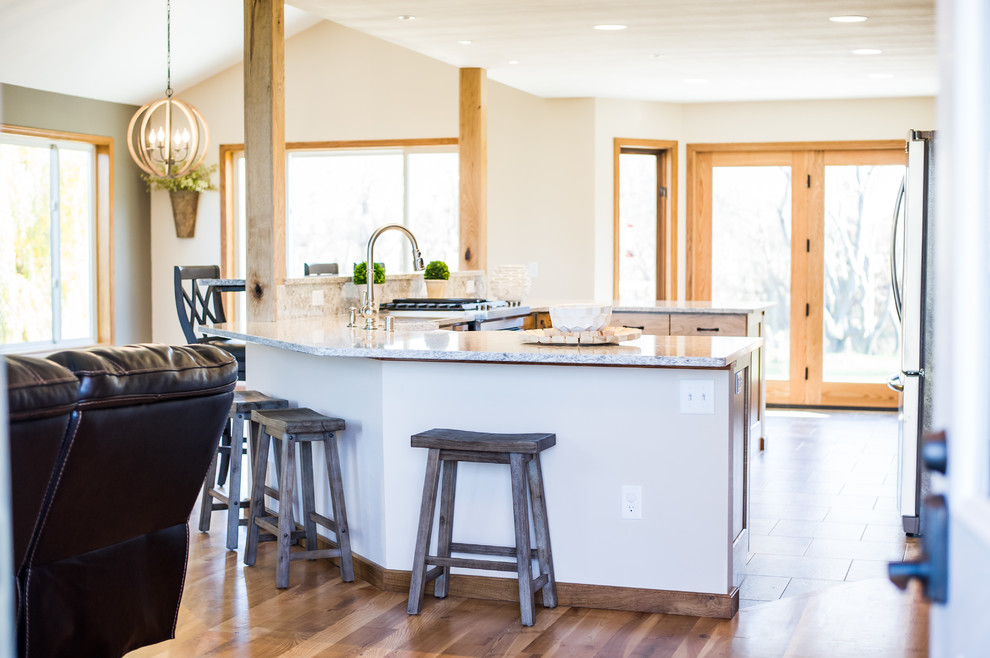 This is an example of a large country u-shaped open plan kitchen in Other with a farmhouse sink, recessed-panel cabinets, purple cabinets, beige splashback, stainless steel appliances, medium hardwood floors, with island and granite benchtops.