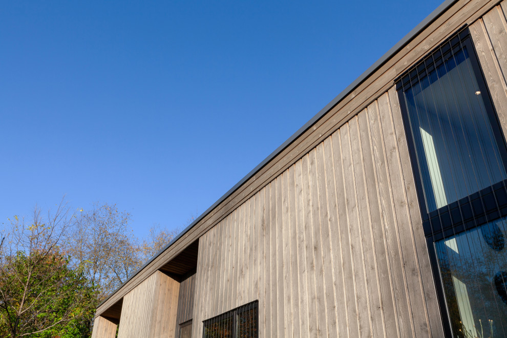 Idee per la facciata di una casa piccola grigia moderna a un piano con rivestimento in legno, copertura in metallo o lamiera e tetto grigio