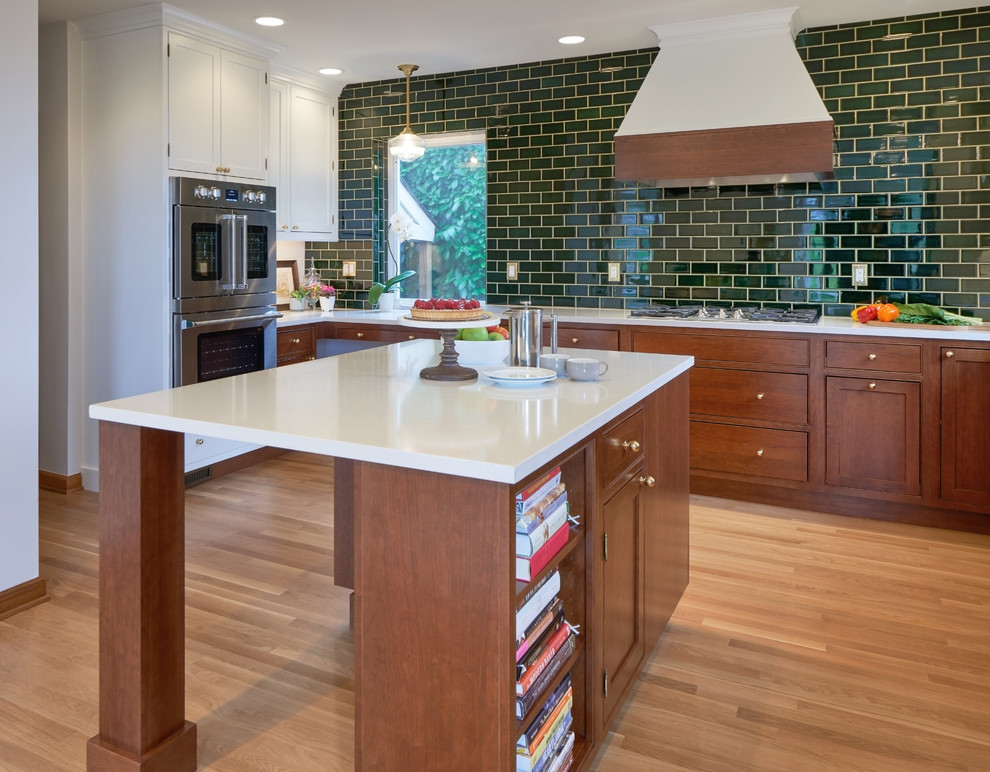 Mid-sized transitional u-shaped medium tone wood floor kitchen photo in Seattle with a farmhouse sink, beaded inset cabinets, white cabinets, quartz countertops, green backsplash, porcelain backsplash, stainless steel appliances, white countertops and an island