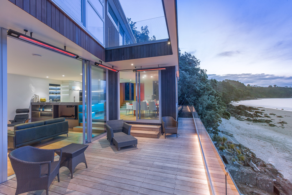 Large trendy glass railing front porch photo in Auckland with decking