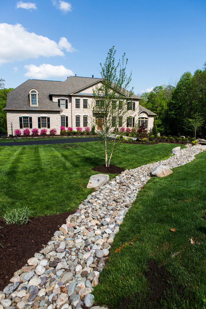 This is an example of an expansive country front yard full sun garden in DC Metro with natural stone pavers.