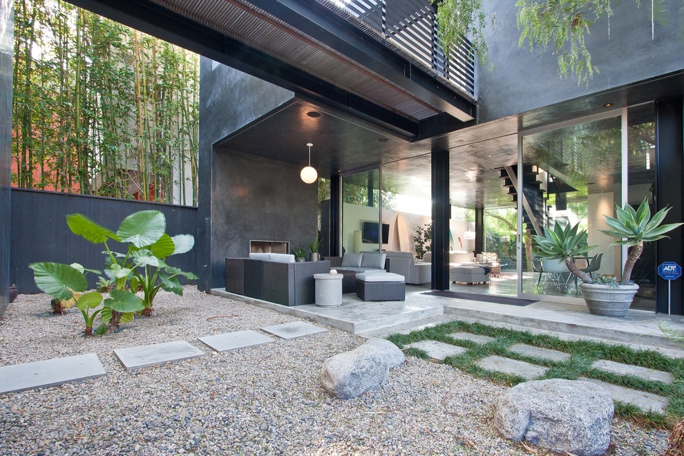 Photo of a mid-sized contemporary courtyard patio in Los Angeles with with fireplace, concrete slab and a roof extension.