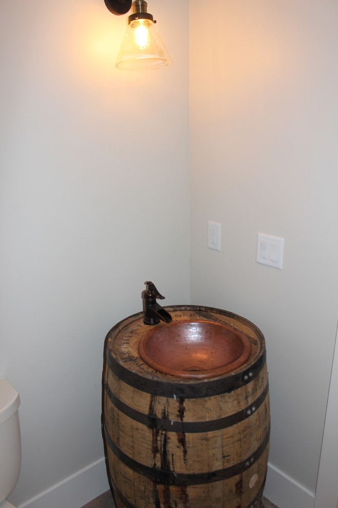 This is an example of a large transitional powder room in Salt Lake City with furniture-like cabinets, distressed cabinets, a two-piece toilet, grey walls and a drop-in sink.