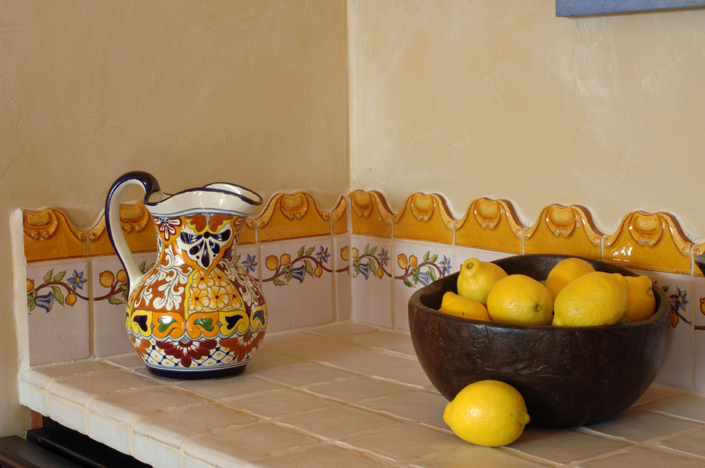 This is an example of a traditional eat-in kitchen in Phoenix with raised-panel cabinets, medium wood cabinets, tile benchtops, multi-coloured splashback and ceramic splashback.