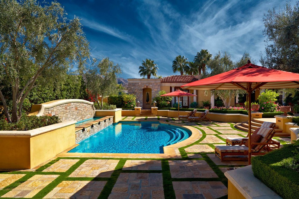 This is an example of a mediterranean courtyard custom-shaped lap pool in Other with a water feature and natural stone pavers.