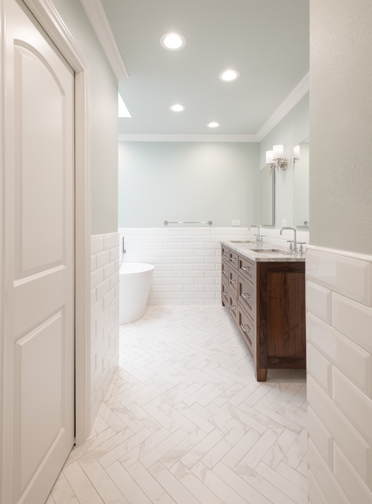 This is an example of a mid-sized transitional master bathroom in Dallas with shaker cabinets, medium wood cabinets, a freestanding tub, an alcove shower, white tile, subway tile, blue walls, porcelain floors, an undermount sink, quartzite benchtops, white floor and grey benchtops.