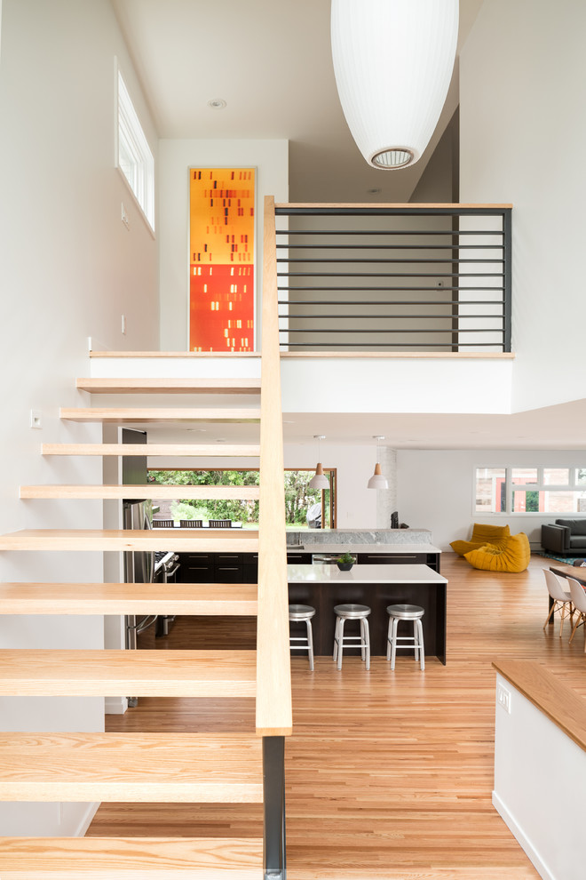 Mid-sized contemporary wood u-shaped staircase in Denver with open risers and metal railing.