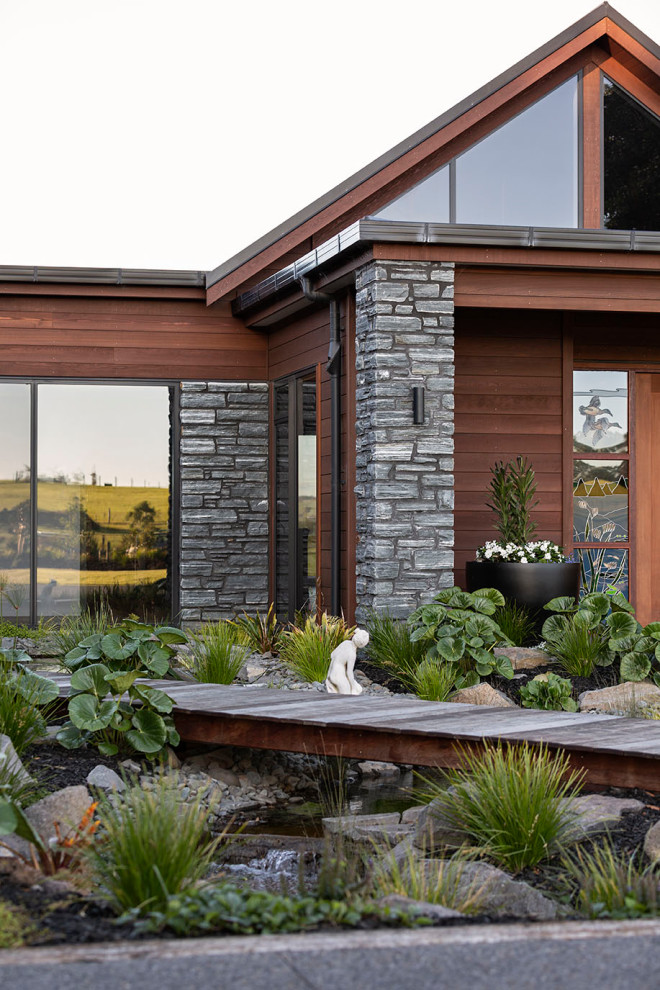 Geräumiges Einfamilienhaus mit Steinfassade, bunter Fassadenfarbe, Satteldach, Blechdach, schwarzem Dach und Wandpaneelen in Auckland