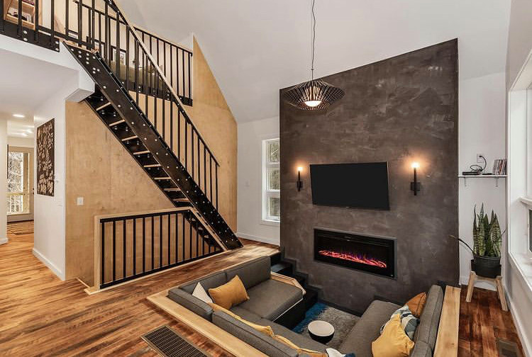 Ejemplo de sala de estar abierta y abovedada ecléctica pequeña con paredes negras, suelo de madera en tonos medios y televisor colgado en la pared