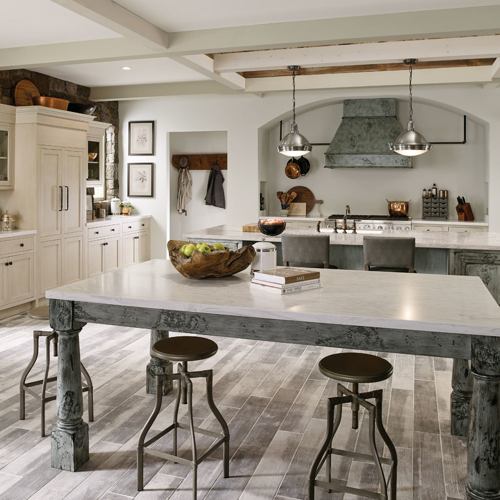 This is an example of an expansive country l-shaped eat-in kitchen in Other with an undermount sink, grey cabinets, stainless steel appliances, multiple islands, grey floor and recessed-panel cabinets.