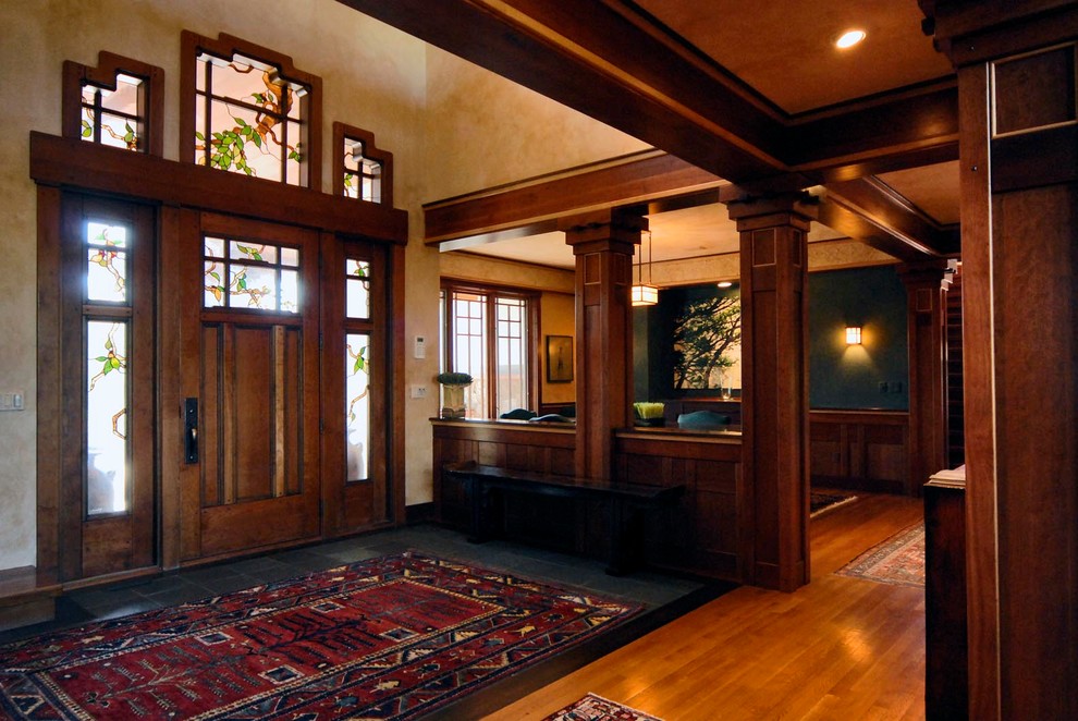 This is an example of an expansive arts and crafts foyer in Denver with beige walls, medium hardwood floors, a single front door and a dark wood front door.