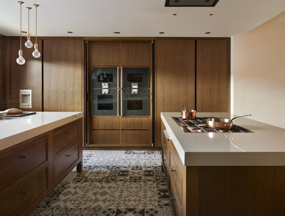 This is an example of a mid-sized eclectic galley separate kitchen in Kent with an undermount sink, raised-panel cabinets, dark wood cabinets, quartzite benchtops, grey splashback, black appliances, porcelain floors and multiple islands.