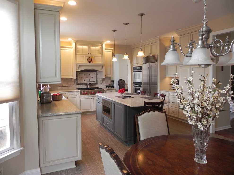 Inspiration for a mid-sized transitional u-shaped light wood floor and brown floor eat-in kitchen remodel with an undermount sink, raised-panel cabinets, white cabinets, granite countertops, beige backsplash, ceramic backsplash, stainless steel appliances and an island