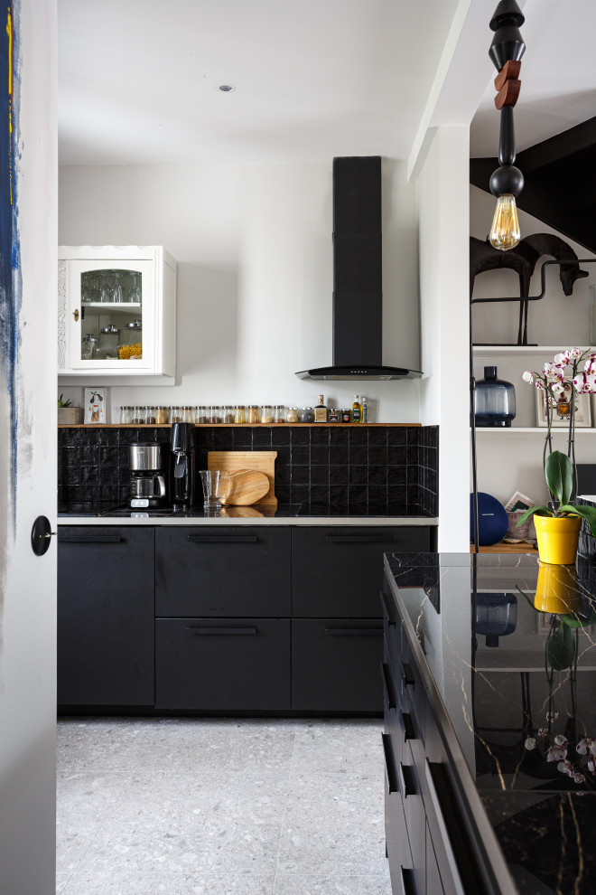 Inspiration for a mid-sized eclectic galley open plan kitchen in Paris with a single-bowl sink, beaded inset cabinets, black cabinets, tile benchtops, black splashback, terra-cotta splashback, panelled appliances, concrete floors, with island, grey floor and black benchtop.