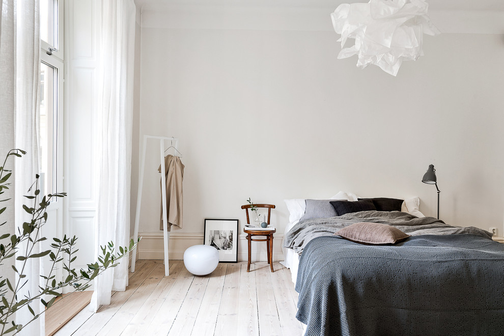Mid-sized scandinavian master bedroom in Stockholm with white walls and painted wood floors.