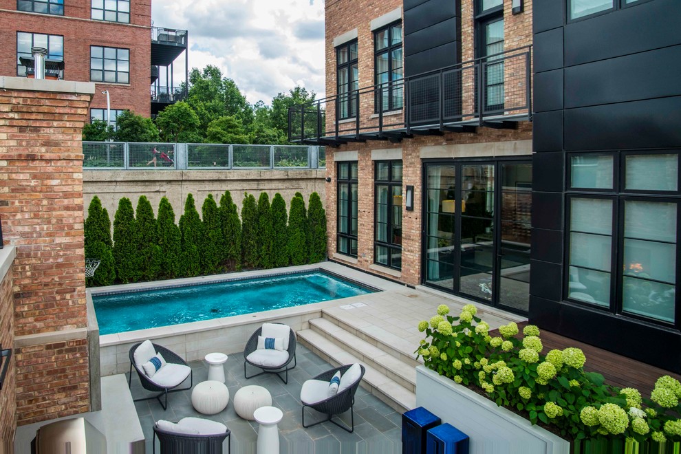 Photo of a small modern courtyard rectangular lap pool in Chicago with a hot tub and natural stone pavers.