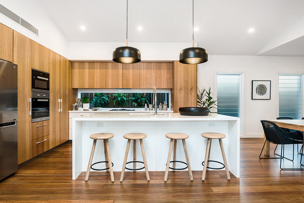 This is an example of a contemporary l-shaped kitchen in Gold Coast - Tweed with an undermount sink, flat-panel cabinets, medium wood cabinets, window splashback, stainless steel appliances, medium hardwood floors, with island and brown floor.