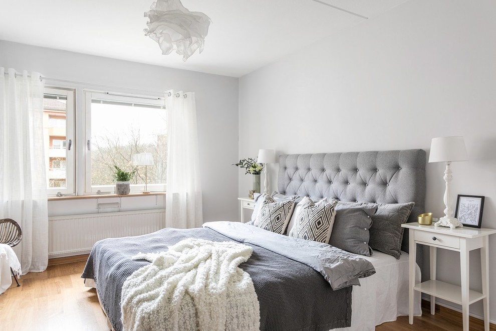 This is an example of a scandinavian bedroom in Gothenburg with white walls, medium hardwood floors and brown floor.