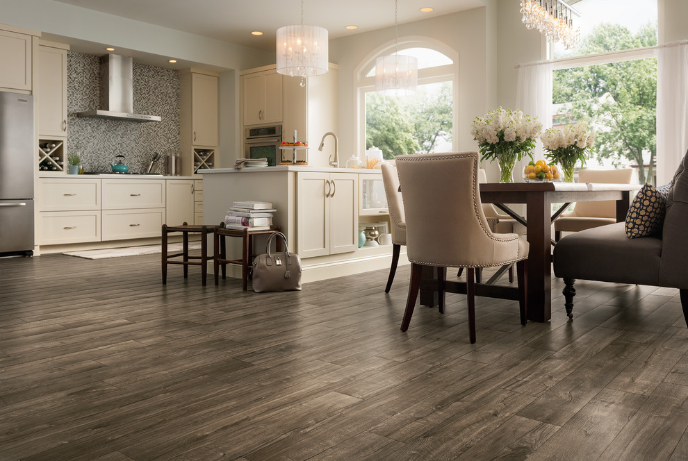 This is an example of a mid-sized traditional l-shaped eat-in kitchen in Other with beige cabinets, grey splashback, laminate floors, a peninsula, shaker cabinets, mosaic tile splashback and stainless steel appliances.