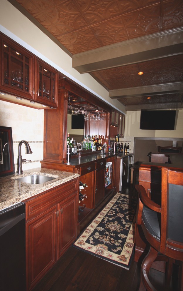 Design ideas for a large country galley seated home bar in DC Metro with an undermount sink, dark wood cabinets, granite benchtops, beige splashback, stone tile splashback and dark hardwood floors.