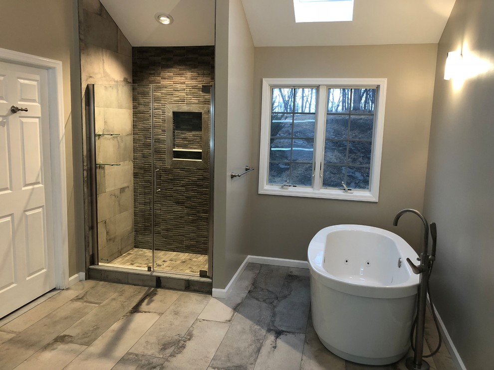 Photo of a large transitional bathroom in Newark with furniture-like cabinets, brown cabinets, a freestanding tub, an open shower, a two-piece toilet, porcelain tile, porcelain floors, an undermount sink, marble benchtops, grey floor and a hinged shower door.