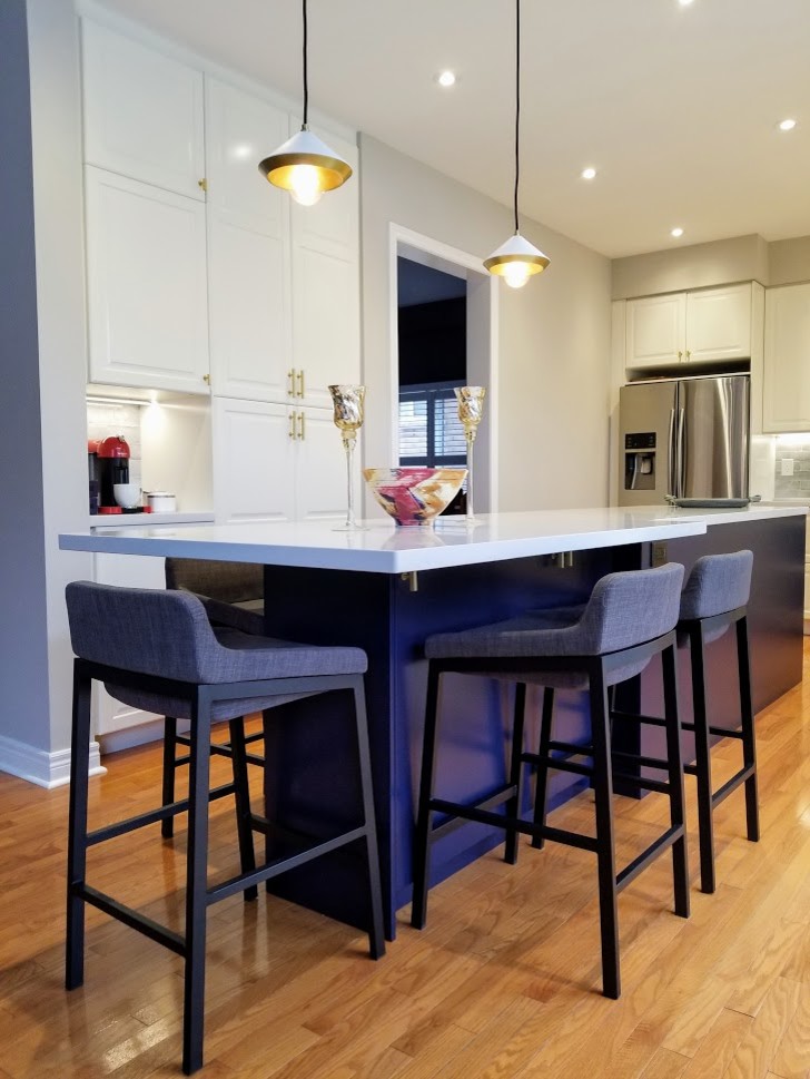 Photo of a large transitional l-shaped open plan kitchen in Toronto with an undermount sink, raised-panel cabinets, white cabinets, quartz benchtops, blue splashback, ceramic splashback, stainless steel appliances, light hardwood floors, with island, orange floor and grey benchtop.