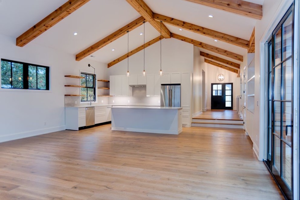 Mid-sized transitional u-shaped medium tone wood floor eat-in kitchen photo in Seattle with a double-bowl sink, raised-panel cabinets, white cabinets, soapstone countertops, white backsplash, stone slab backsplash, stainless steel appliances and an island