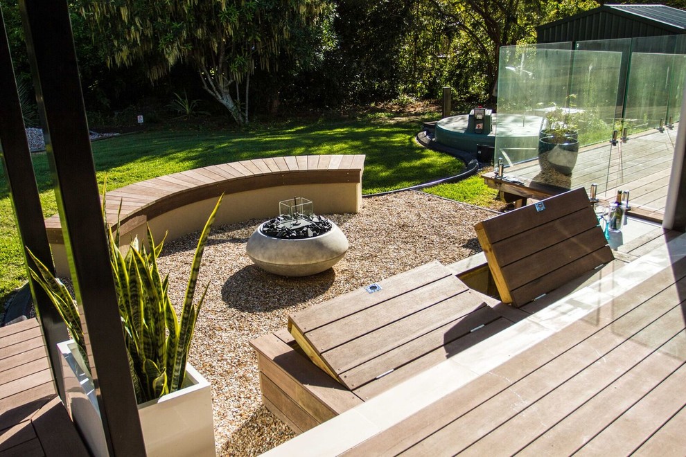 Inspiration for a contemporary backyard partial sun formal garden in Brisbane with a fire feature and gravel.