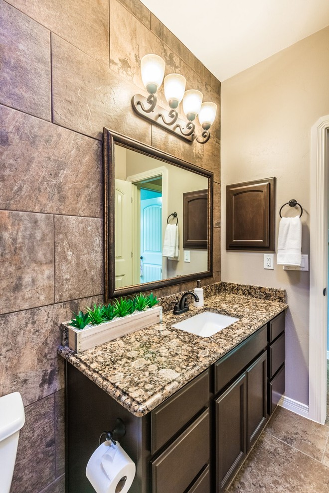 Example of a mid-sized transitional 3/4 brown tile and ceramic tile ceramic tile home design design in Austin with raised-panel cabinets, brown cabinets, a one-piece toilet, brown walls, a drop-in sink and granite countertops