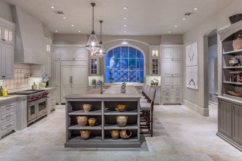 Example of a large transitional l-shaped travertine floor eat-in kitchen design in Houston with two islands, limestone countertops, beige backsplash, ceramic backsplash, stainless steel appliances, gray walls, a farmhouse sink, raised-panel cabinets and gray cabinets