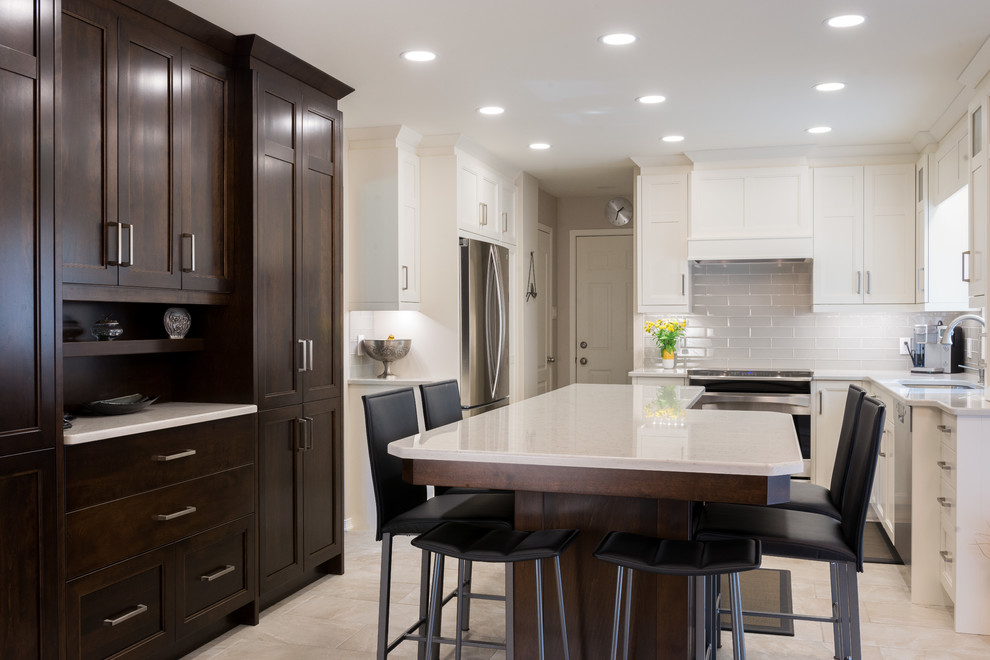 Photo of a mid-sized contemporary u-shaped eat-in kitchen in Ottawa with an undermount sink, shaker cabinets, white cabinets, quartz benchtops, white splashback, subway tile splashback, stainless steel appliances, ceramic floors and with island.