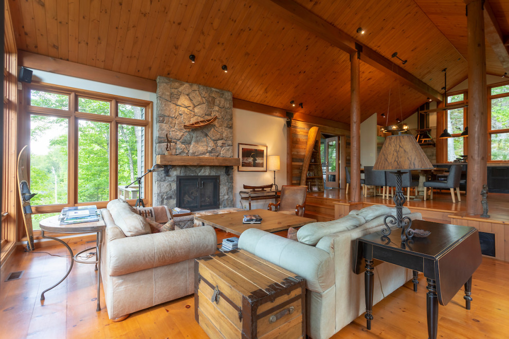 Inspiration for an expansive country formal open concept living room in Montreal with white walls, medium hardwood floors, a wood stove, a stone fireplace surround, no tv and orange floor.