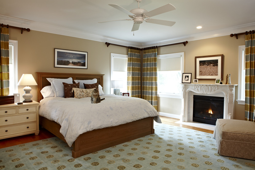 Design ideas for a large traditional master bedroom in DC Metro with beige walls, a standard fireplace, light hardwood floors and brown floor.