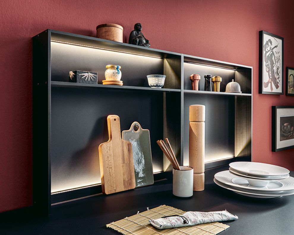 Large asian l-shaped open plan kitchen in Nuremberg with flat-panel cabinets, black cabinets, red splashback, black appliances, with island and white benchtop.