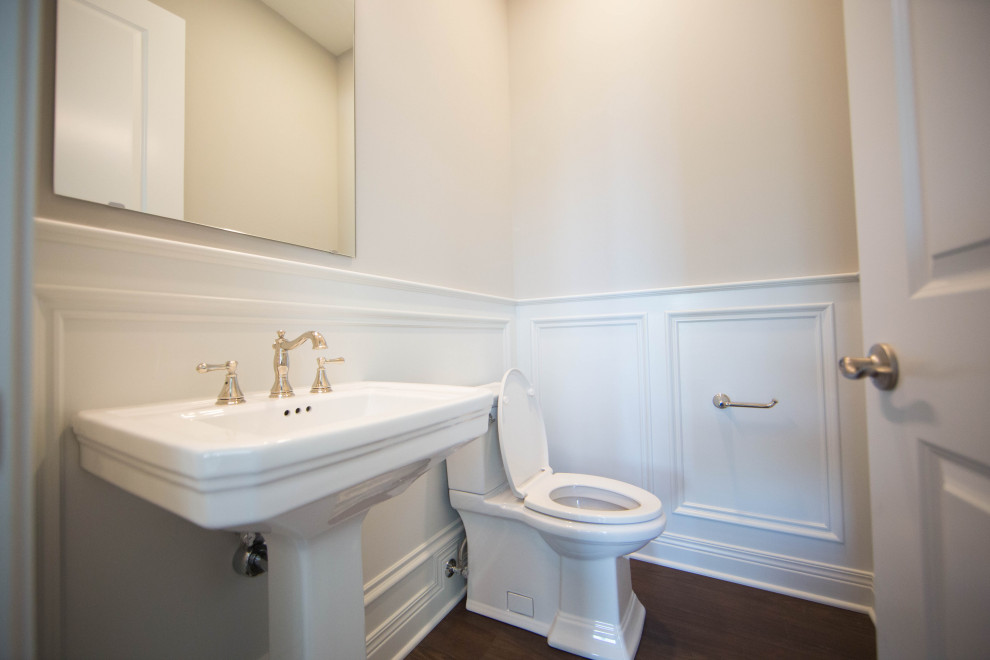 Mittelgroßes Klassisches Badezimmer En Suite mit Wandtoilette mit Spülkasten, beiger Wandfarbe, braunem Holzboden, Sockelwaschbecken, braunem Boden, vertäfelten Wänden und Einzelwaschbecken in Indianapolis