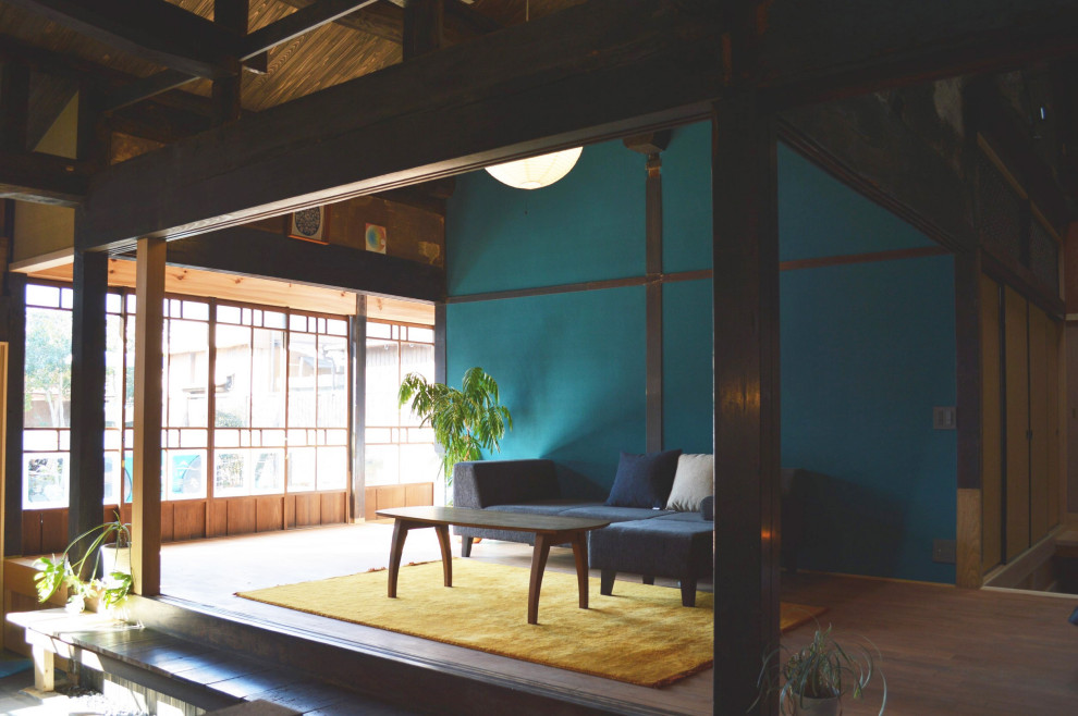 Идея дизайна: открытая гостиная комната среднего размера в восточном стиле с синими стенами, паркетным полом среднего тона, отдельно стоящим телевизором и балками на потолке без камина