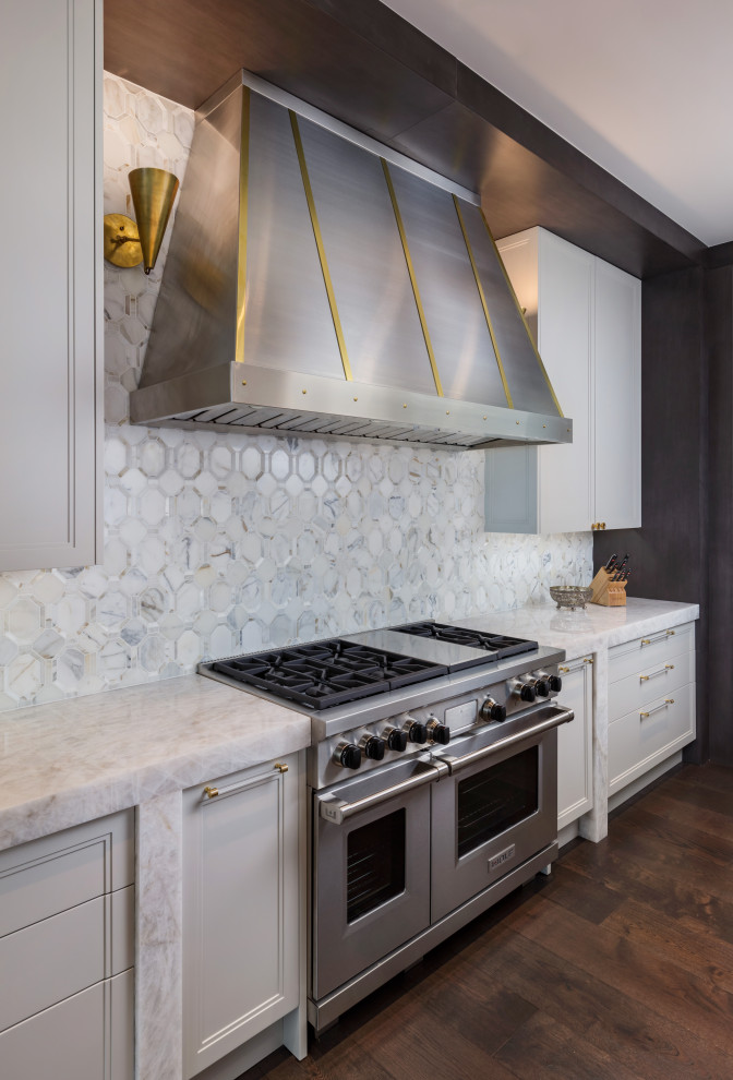 Idéer för ett mellanstort klassiskt vit u-kök, med en undermonterad diskho, luckor med infälld panel, vita skåp, marmorbänkskiva, vitt stänkskydd, stänkskydd i metallkakel, rostfria vitvaror, mörkt trägolv, en köksö och brunt golv