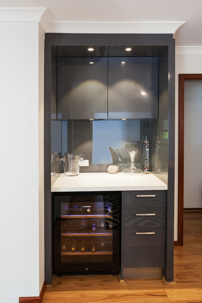 Inspiration for a modern kitchen in Perth with flat-panel cabinets, grey cabinets, quartz benchtops, metallic splashback, glass sheet splashback, stainless steel appliances and white benchtop.
