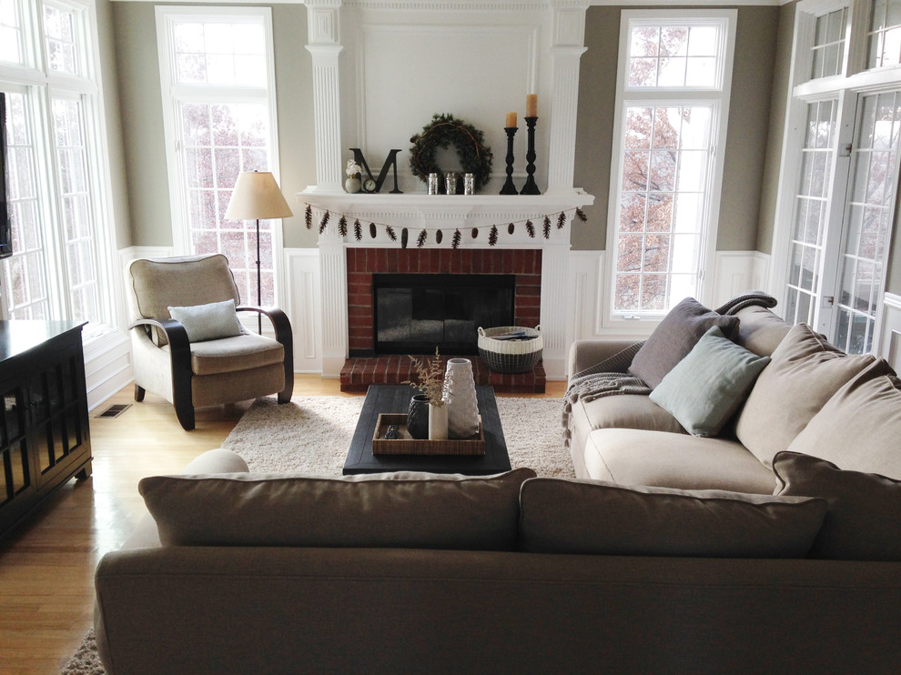 This is an example of a mid-sized traditional formal enclosed living room in Other with beige walls, medium hardwood floors, a standard fireplace, a brick fireplace surround and a wall-mounted tv.