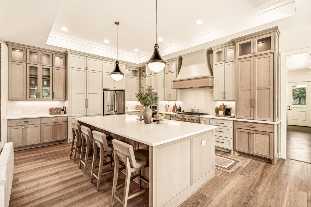 Example of a mid-sized transitional l-shaped vinyl floor and tray ceiling eat-in kitchen design in Dallas with an undermount sink, shaker cabinets, light wood cabinets, quartz countertops, white backsplash, quartz backsplash, stainless steel appliances, an island and white countertops