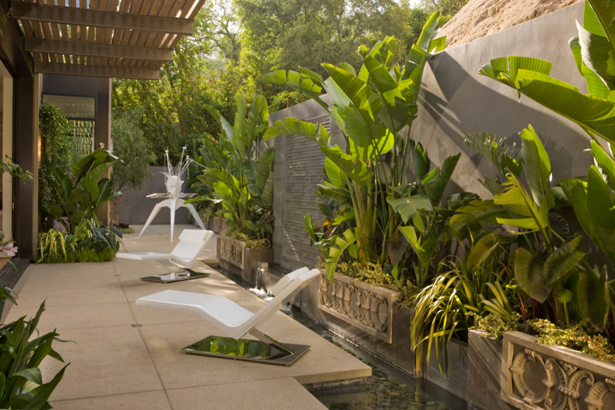 This is an example of a mid-sized contemporary side yard patio in Los Angeles with a water feature, concrete slab and an awning.