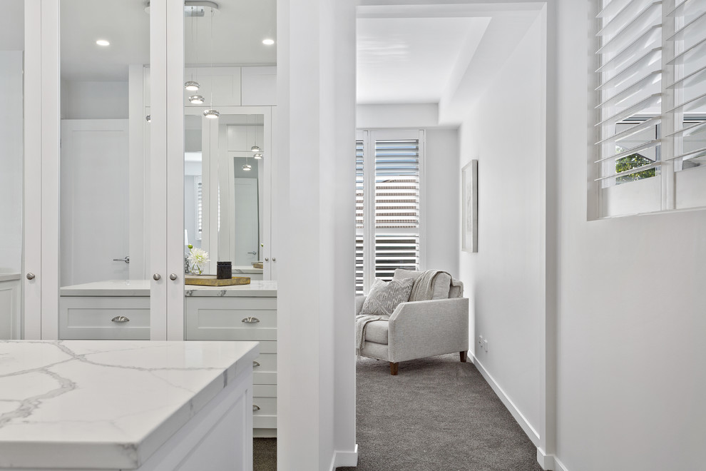 Design ideas for a large contemporary gender-neutral walk-in wardrobe in Brisbane with white cabinets, carpet, shaker cabinets and grey floor.