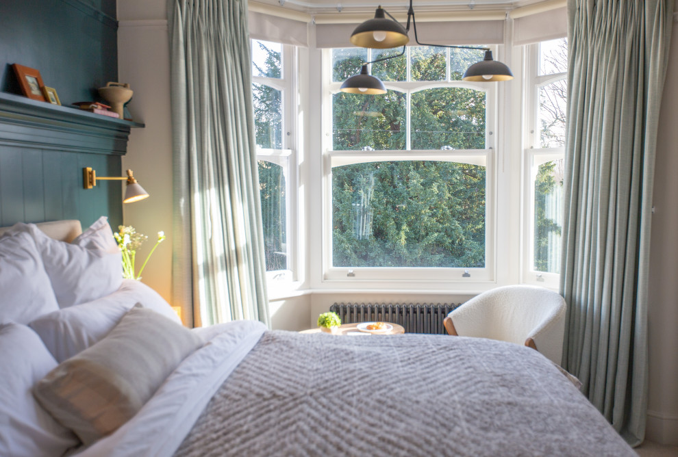 Mid-sized transitional master bedroom in London with blue walls, carpet, beige floor and panelled walls.